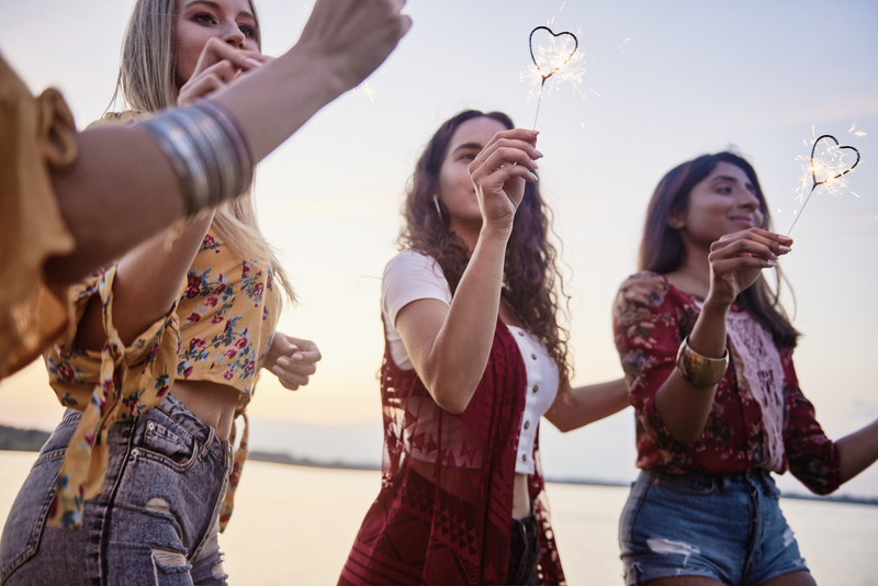 Three beautiful women having fun with sparklers on the beach